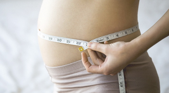 Беременная женщина измеряет живот
